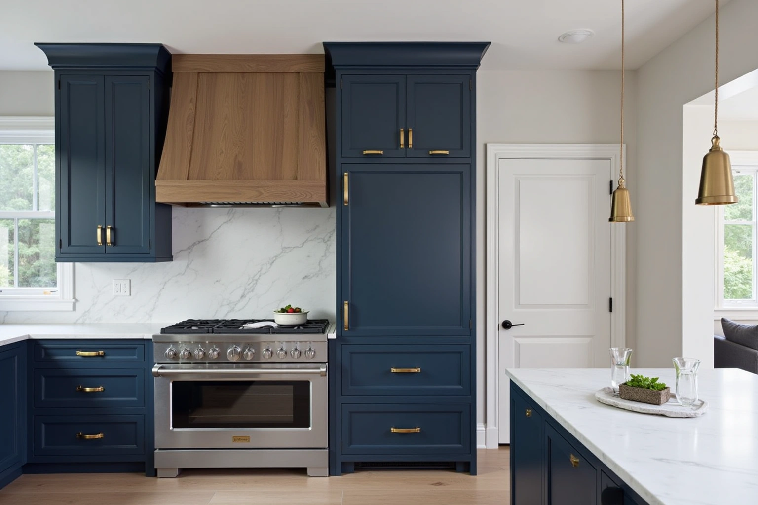 Deep navy floor-to-ceiling cabinets with brass hardware, a white oak range hood, a paneled refrigerator and marble surfaces.
